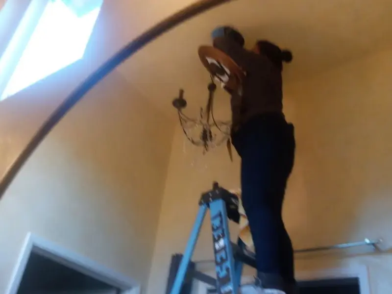 Electrician installing a chandelier in a Forest City residence